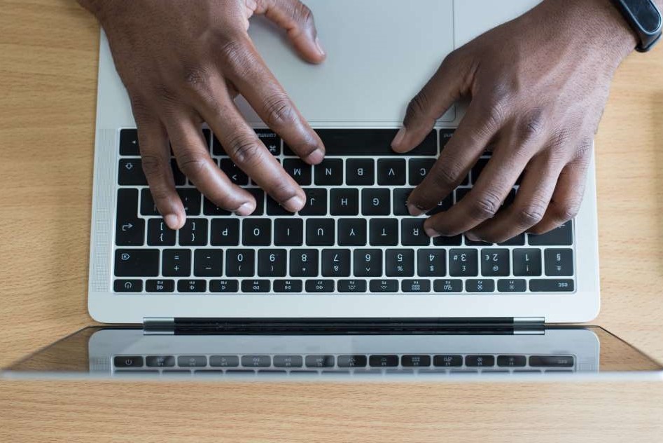 Ein Geschäftsmann, sitzt am Laptop und tippt in die Tastatur. Die FIN-Abfrage ist online über viele Dienste oder Portale möglich.