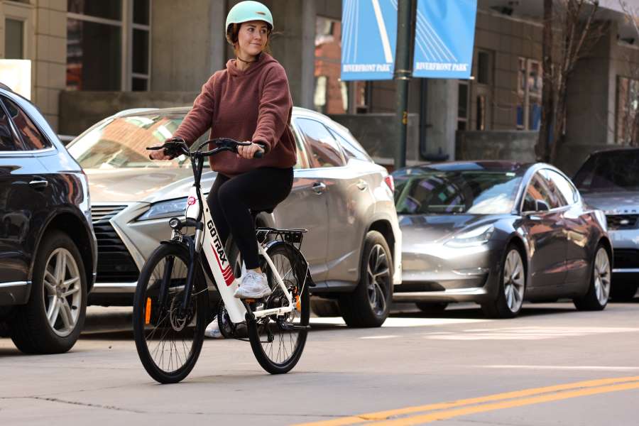 Eine Mitarbeiterin eines Unternehmens fährt auf einem Dienstrad durch die Stadt.