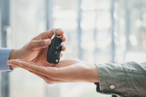 Eine Hand übergibt einem anderen Mitarbeitenden einen Autoschlüssel. Das Bild steht für die gemeinsame Nutzung von Poolfahrzeugen im Unternehmen. Poolfahrzeuge erhöhen die Auslastung und Effizienz im Fuhrpark – mit klarer Schlüsselübergabe, digitaler Planung und professioneller Fahrzeugverwaltung.