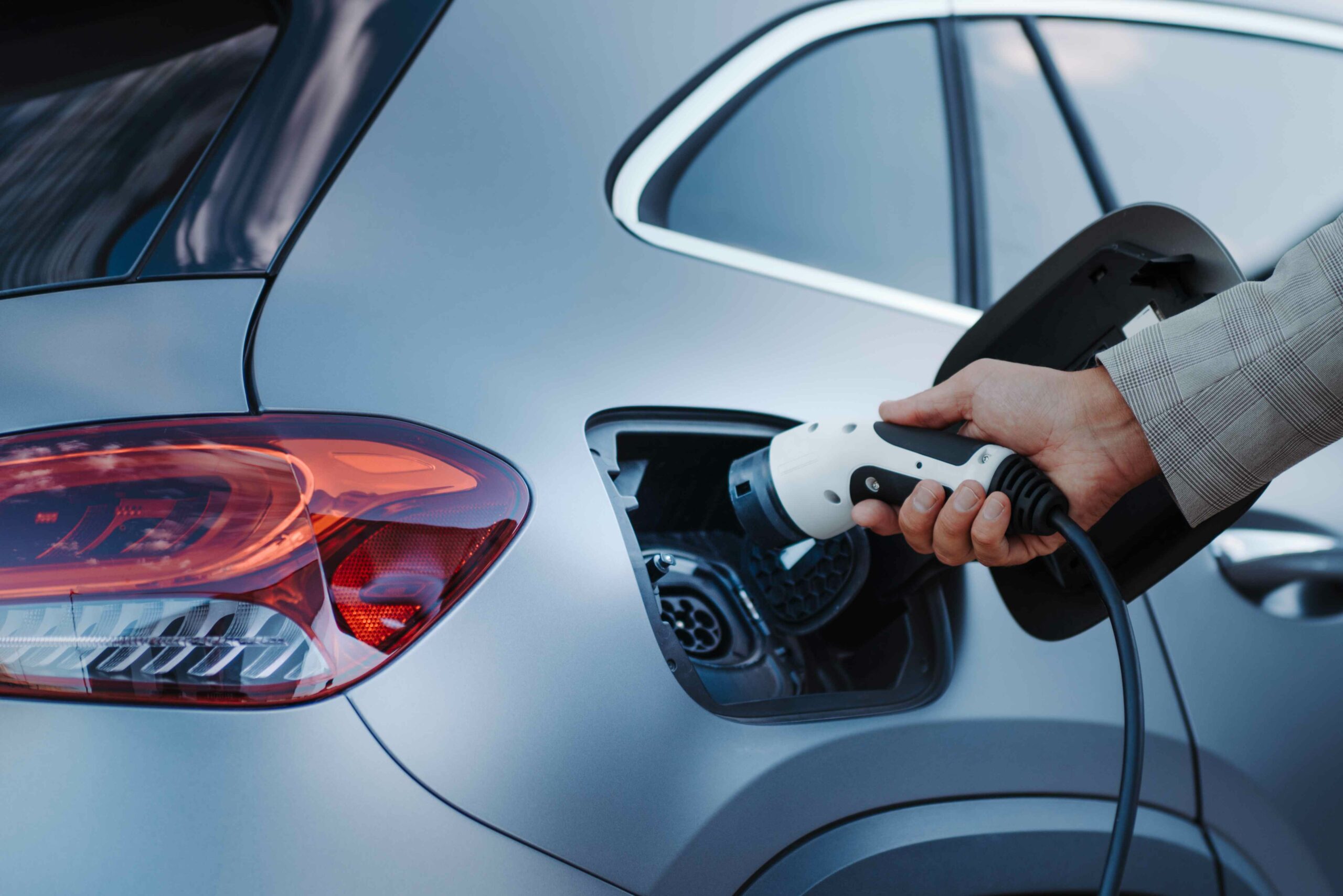 Eine Person steckt ein Ladekabel in ein Elektroauto. Fleethouse unterstützt Unternehmen dabei, ihre Fahrzeugflotte effizient zu verwalten, Elektromobilität einfach einzubinden und den Verwaltungsaufwand deutlich zu verringern.