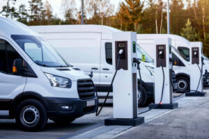 Weiße Transporter laden an E-Ladestationen. Das Bild zeigt, wie Unternehmen ihren Fuhrpark elektrifizieren. Fleethouse unterstützt dabei mit smarter Fuhrparksoftware, effizienter Ladeplanung und nachhaltiger Mobilität für eine zukunftssichere Flotte.