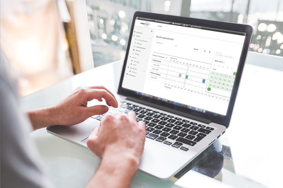 Person bedient am Laptop eine Poolfahrzeug-Software von Fleethouse mit Kalenderübersicht zur digitalen Buchung, Verwaltung und Auswertung gemeinsam genutzter Firmenfahrzeuge.