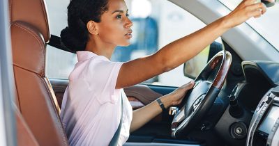 Woman looks in the rearview mirror of her leasing car