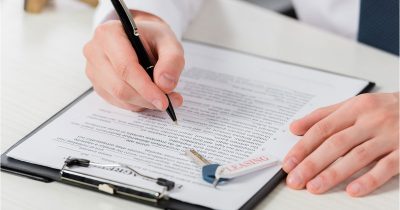 Eine Person unterschreibt einen Leasingvertrag, daneben liegt ein Autoschlüssel mit Anhänger „Leasing“. Die Checkliste zur Leasingrückgabe von Fleethouse hilft Fuhrparkverantwortlichen, Fahrzeugrückgaben strukturiert, rechtssicher und ohne versteckte Kosten vorzubereiten – digital unterstützt und effizient umsetzbar.