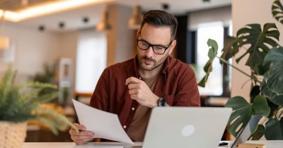 Ein Fuhrparkmanager arbeitet am Laptop und prüft Dokumente. Fleethouse unterstützt Unternehmen bei der effizienten Verwaltung des Fuhrparks, indem es Prozesse optimiert, Kosten senkt und den administrativen Aufwand reduziert.