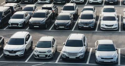 Ein Parkplatz voller Fahrzeuge verschiedener Marken und Modelle, die in Reihen geparkt sind. Logistik und Koordination spielen eine zentrale Rolle im effizienten Fuhrparkmanagement.