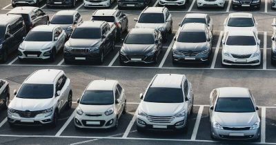 Ein Parkplatz voller Fahrzeuge verschiedener Marken und Modelle, die in Reihen geparkt sind. Logistik und Koordination spielen eine zentrale Rolle im effizienten Fuhrparkmanagement.