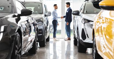 Zwei M&auml;nner geben sich in einem Autohaus die Hand, umgeben von verschiedenen Fahrzeugen. Fleethouse bietet mit dem Leasing-Ratgeber umfassende Informationen und digitale L&ouml;sungen, um das passende Leasingangebot einfach, transparent und effizient f&uuml;r Unternehmen und Selbstst&auml;ndige zu finden.