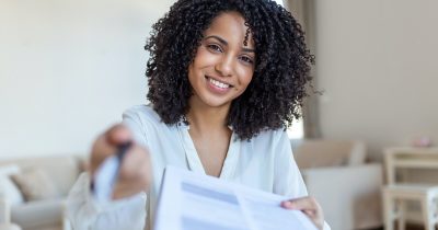 Eine Frau lächelt, während sie einen Vertrag für ein Poolfahrzeug unterzeichnet. Die Vereinbarung ermöglicht eine einfache Nutzung von Firmenfahrzeugen. Fleethouse bietet flexible Lösungen zur Poolfahrzeug-Vereinbarung und sorgt für transparente und effiziente Verwaltung des Fuhrparks.