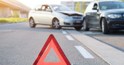Zwei Autos stehen nach einem Unfall besch&auml;digt auf der Stra&szlig;e, im Vordergrund ein aufgestelltes Warndreieck. Fleethouse bietet digitale Unterst&uuml;tzung bei der Schadenabwicklung im Fuhrpark &ndash; schnell, transparent und effizient f&uuml;r Fuhrparkleiter und Unternehmen.