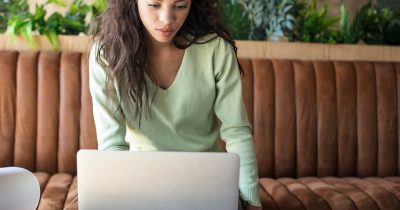 Dienstwagenfahrerin sitzt am Laptop und nimmt online an einem E-Learning-Kurs teil für die elektronische Fahrerunterweisung nach UVV.